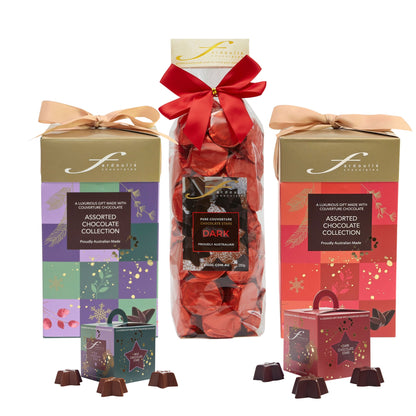 Fardoulis Christmas chocolate gift selection with two ribbon-tied tall boxes, a dark chocolate stars gift bag, and milk and dark chocolate star boxes.”