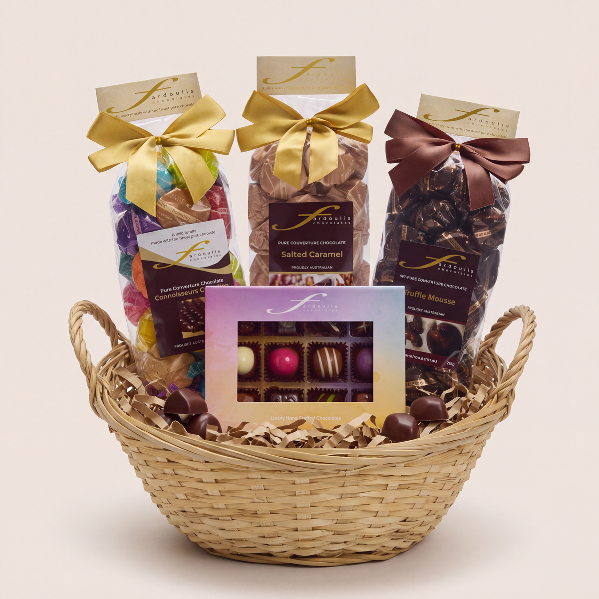 “Fardoulis Indulgent Classic Chocolate Gift Hamper in a woven basket with three ribbon-tied chocolate bags and a windowed assorted chocolate box.”