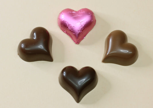Shop pink foiled chocolate hearts in strawberry mousse, milk or dark chocolate, made from pure couverture chocolate. Perfect for favours and gifts.